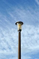 Modern Public Street Light on Single Concrete Post against Blue Sky 