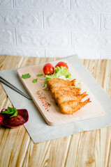 Butterfly ebi furai shrimp served with tomato and lettuce on a wooden chopping board along with ketchup