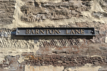 Old Cast Iron Street Sign on Rough Textured Stone Wall 