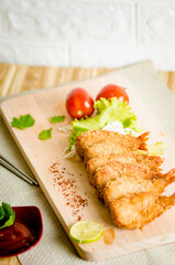 Butterfly ebi furai shrimp served with tomato and lettuce on a wooden chopping board along with ketchup