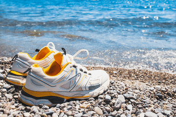 A pair of white sneakers on the pebbled beach - time to swim and cool off after a long walk