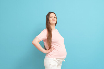 happy young pregnant woman in pink t-shirt on blue background