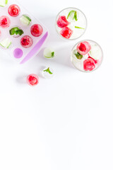 Raspberry and lime in ice cubes on white table top view copy space