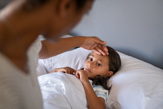 Worried mother checking daughter temperature