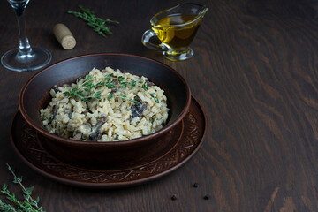 Mediterranean creamy risotto or Italian arborio rice dish cooked with broth, mushrooms, onion, white wine, olive oil and parmesan cheese on dark brown wooden background. Image with copy space