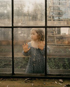 Little girl standing behind a glass window