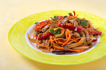 Korean eggplants. Spicy vegetable salad with eggplant, bell peppers, carrots, onions on a plate on a bright background.