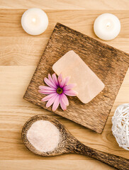 Bar of orange dry Himalayan crystal Salt Soap on wooden background with wooden spoon with pink orange Himalayan crystal Salt grains in. Flower blossom decoration. Alternative medicine concept.