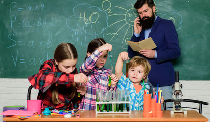 Our goal is to find the cure. happy children & teacher. back to school. kids in lab coat learning chemistry in school laboratory. doing experiments with liquids in chemistry lab. chemistry lab