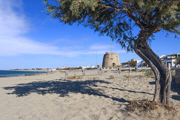 Torre Mozza beach in Salento, Apulia (Italy). The ruined watchtower overlooks the long beach of Torre Mozza, with fine sand, lapped by the crystal clear water.