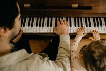 Father and child playing piano together