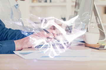 Handshake hologram drawing with businessman working on computer on background. Double exposure.