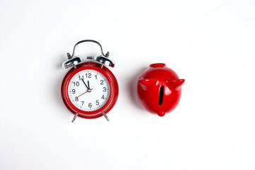 Classic alarm clock and red piggy bank on a white background.