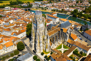 Fototapeta na wymiar Picturesque summer view of historic areas of Saintes located on Charente river looking out over cathedral bell tower in Flamboyant Gothic style, Charente-Maritime, France..