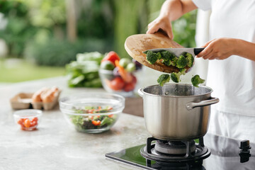 Human hands cooking vegetables salad in open kitchen