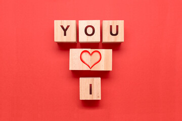 Wooden dice with a heart and the words I and YOU on a red background