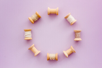 Fototapeta na wymiar Wooden spools of thread for sewing on lilac background