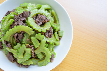 Stir-fried beef with bitter gourd on a dish of home cooking on wooden table