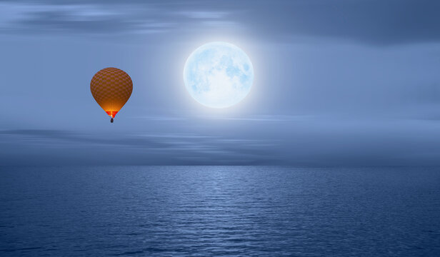 Hot air balloon flying over calm sea moon at night in the background full " Elements of this image furnished by NASA"