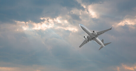 White passenger airplane in the clouds at sunset - Travel by air transport