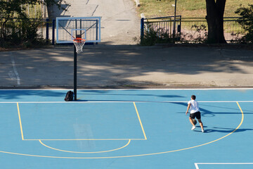 young man training with a ball on an outdoor basketball court