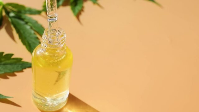 Woman hand using dropper with cbd oil dripping in to glass bottle