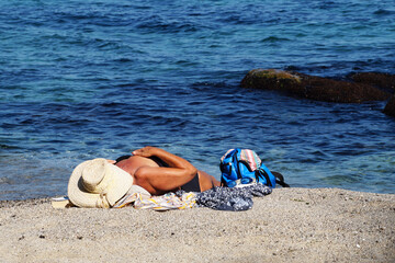 aged woman sunbathes on the sea beach