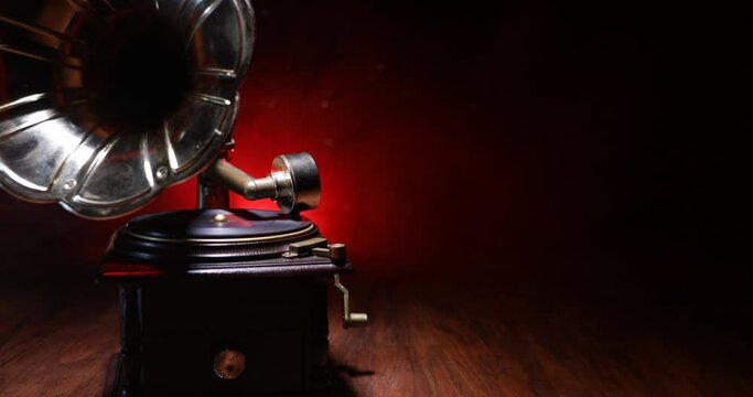 Music concept. Old gramophone on a dark background. Retro gramophone with disc on wooden table with toned backlight. Slider shot