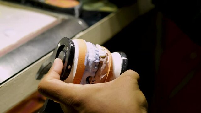 Hands of a man working making a prosthetic tooth. Close up of hands working with a prosthetic tooth