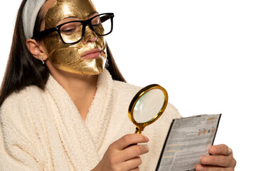 young woman with golden mask reading instructions from the product packaging