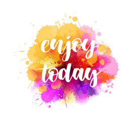 Fototapeta premium Enjoy today - handwritten modern calligraphy lettering on multicolored watercolor splash background. Inspirational handlettering.