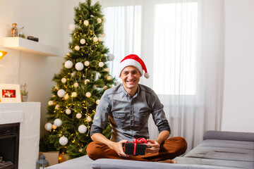 Smiling man opening Christmas gifts at home
