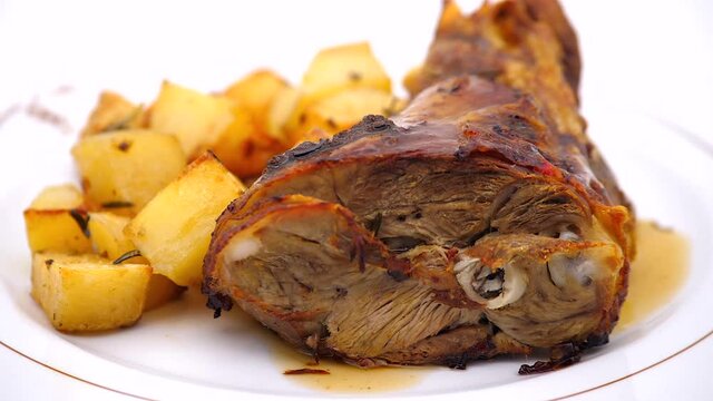 Stinco di magliale con patate al forno su piatto che gira