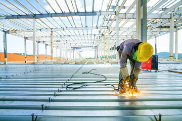 Welder are welds re-bar shear keys metal deck slab of mezzanine floor under the construction building in the factory with blue sky - obrazy, fototapety, plakaty