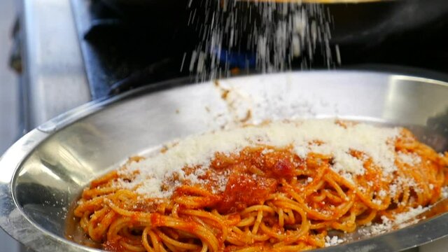 spolverata di formaggio pecorino su spaghetti all'amatriciana, Italia, Roma - sprinkling of pecorino cheese on spaghetti all'amatriciana, Italy, Rome.