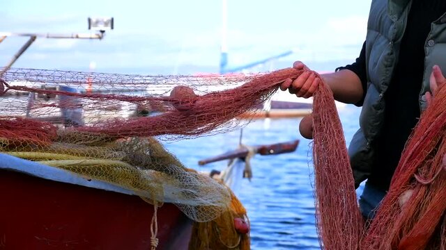 pescatore sistema la rete da pesca sulla sua barca.  Italia.