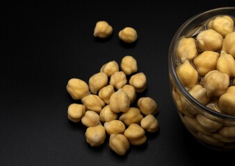 Chickpeas hydrating in a glass with water on black background