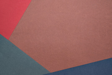 Three sheets of colored paper on a brown background. Red, green, blue. Minimalistic composition. Background for text or design. Empty right side. Top view