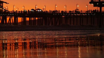 Fototapeta na wymiar California summertime beach aesthetic, golden sunset. Vivid sky over pacific ocean waves. Santa Monica popular resort, Los Angeles CA USA. Famous pier against atmospheric moody evening sundown in LA