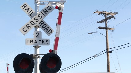 Level crossing warning signal in USA. Crossbuck notice and red traffic light on rail road...