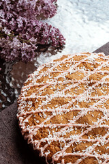 Festive cake decorated with sprinkles lies on glass table with sprig of deer. Delicate cake cooked for whole family. Big pie on table. Cake decorated with coconut and sauce. Vertical photo.