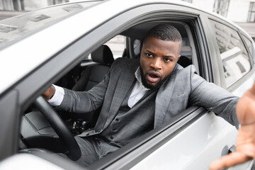 Angry black man driver gesturing and shouting while driving car