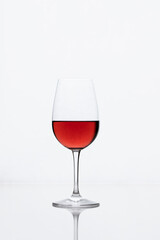 Red wine glass glossy white background with reflection. Simple minimalist image 