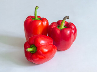 Three red bell peppers on a light background