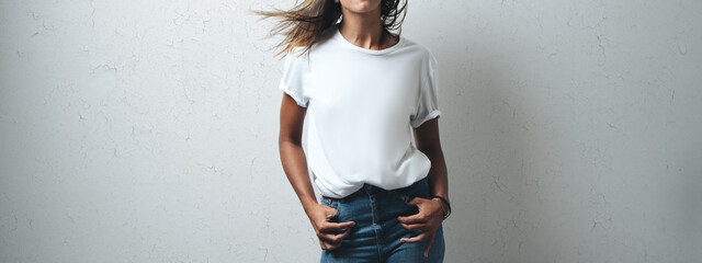 Joyful woman in white blank t-shirt, grunge wall, horizontal studio portrait. Wide screen, panoramic
