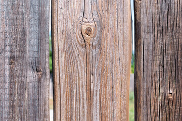 The surface of an old wooden fence, close-up. Brown background. Faded from the sun, dry crooked...