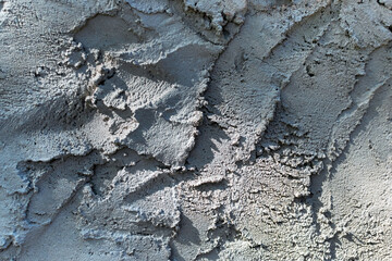 Uneven rough concrete wall surface, gray plaster texture, grainy cement background with textured layers and shadows with light.