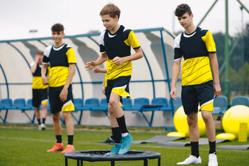 Obraz premium Soccer training trampoline. Group of young boys in sports football club practicing on jumping trampoline. Youth athletes improving stability skills