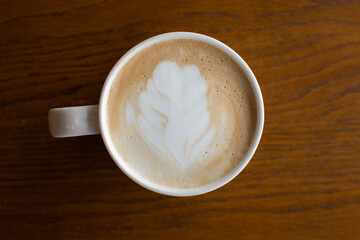 Top view white coffee cup with foam latte art On a brown wooden table