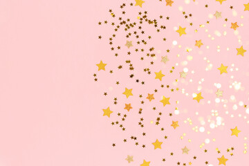 Gold stars confetti scattered on a pink pastel background. Holidays colorful composition with copy space.
